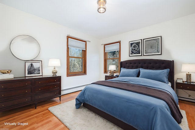 bedroom with light wood-type flooring and a baseboard heating unit