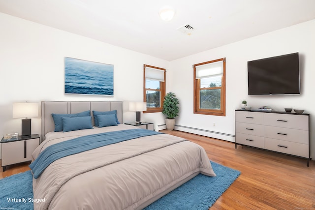 bedroom featuring light hardwood / wood-style flooring and a baseboard heating unit