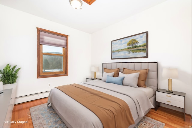 bedroom featuring light wood-type flooring and a baseboard heating unit