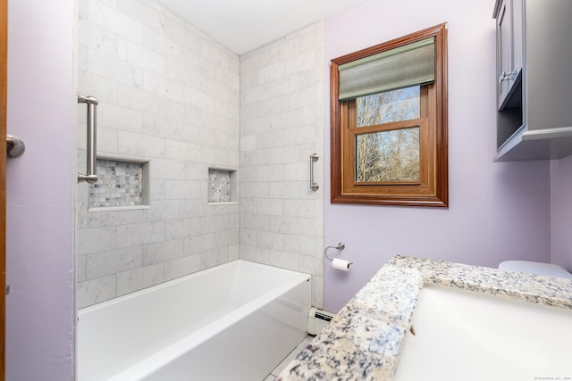 bathroom featuring vanity, tiled shower / bath, and a baseboard heating unit