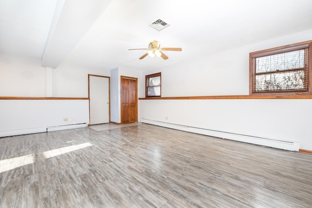 empty room with ceiling fan, wood-type flooring, plenty of natural light, and baseboard heating