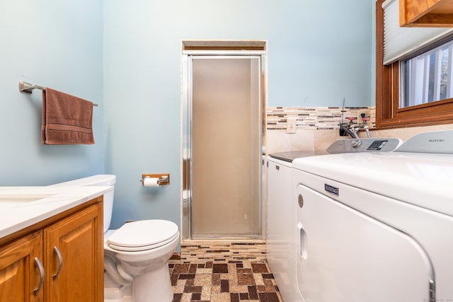 bathroom featuring vanity, toilet, washer and clothes dryer, and a shower with shower door