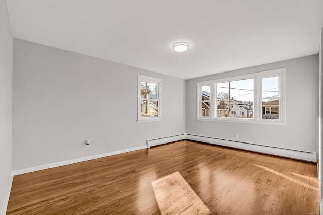 empty room with hardwood / wood-style floors and a baseboard heating unit