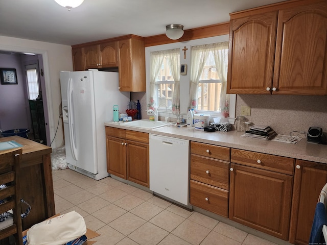 kitchen featuring light tile patterned floors, white appliances, tasteful backsplash, and sink