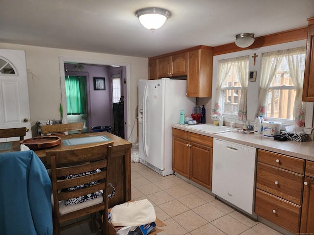 kitchen with light tile patterned floors, white appliances, and sink