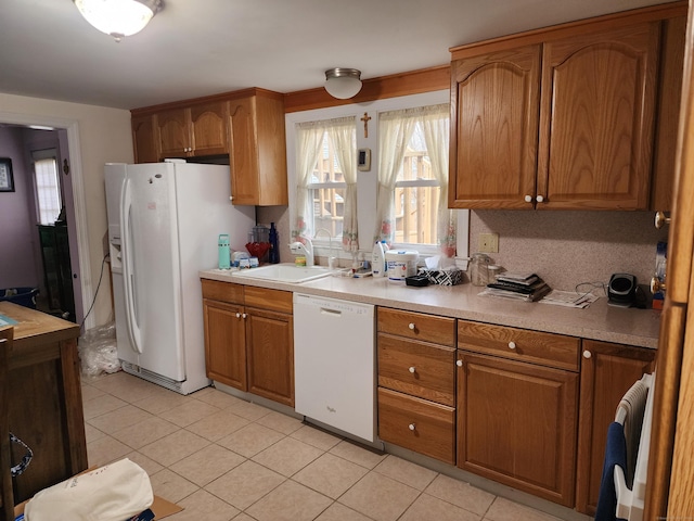 kitchen featuring light tile patterned floors, white appliances, tasteful backsplash, and sink