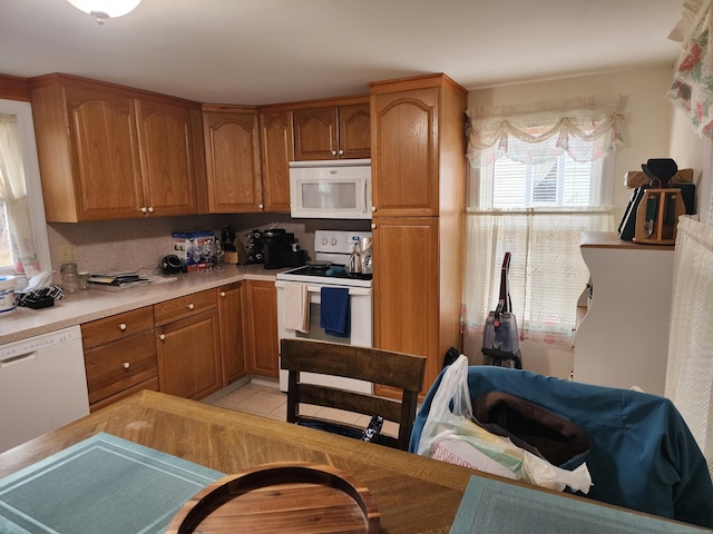 kitchen with light tile patterned floors, white appliances, and a wealth of natural light