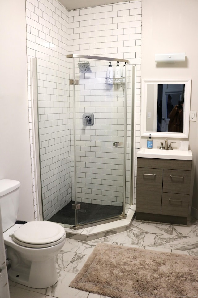 bathroom with vanity, toilet, and a shower with door