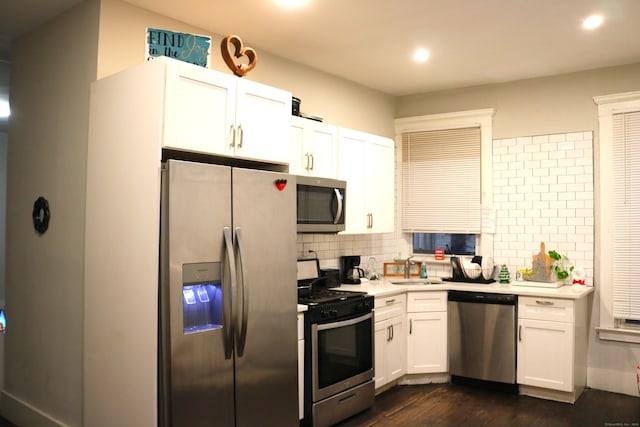 kitchen featuring sink, dark wood-type flooring, decorative backsplash, white cabinets, and appliances with stainless steel finishes