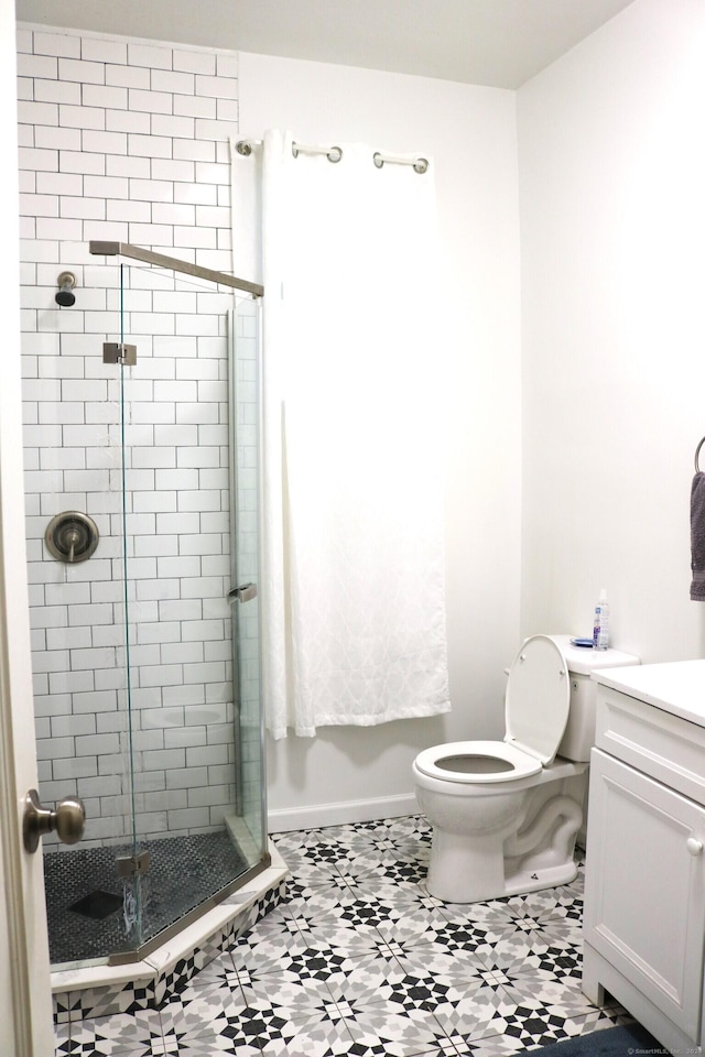 bathroom featuring tile patterned flooring, vanity, toilet, and a shower with shower door