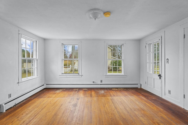 empty room featuring a baseboard radiator, a wealth of natural light, and light hardwood / wood-style flooring