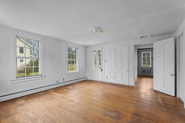 unfurnished room with a healthy amount of sunlight, wood-type flooring, and baseboard heating