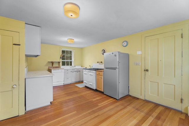 kitchen featuring white cabinetry, light hardwood / wood-style floors, and white appliances