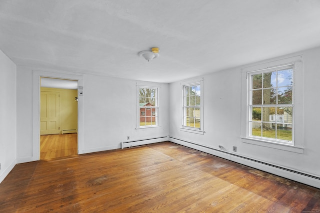 empty room with hardwood / wood-style flooring and a baseboard heating unit