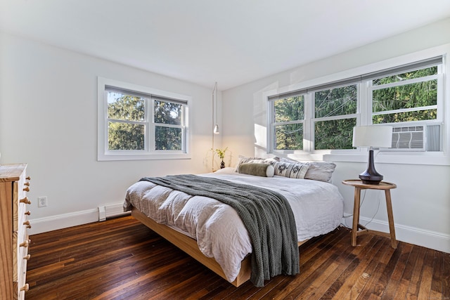 bedroom with dark hardwood / wood-style floors and a baseboard heating unit