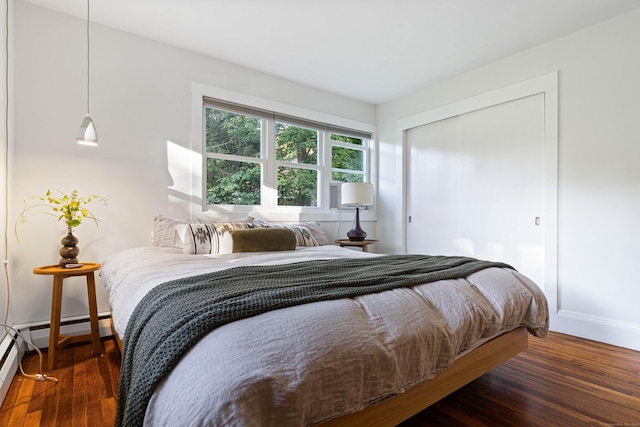 bedroom featuring dark hardwood / wood-style flooring, a baseboard radiator, and a closet