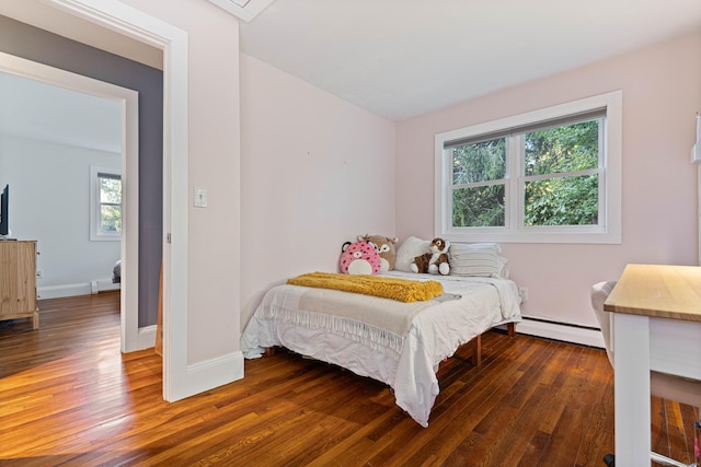 bedroom with multiple windows, dark wood-type flooring, and a baseboard heating unit