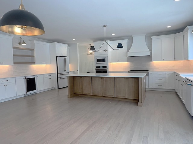 kitchen with appliances with stainless steel finishes, custom exhaust hood, white cabinets, and pendant lighting