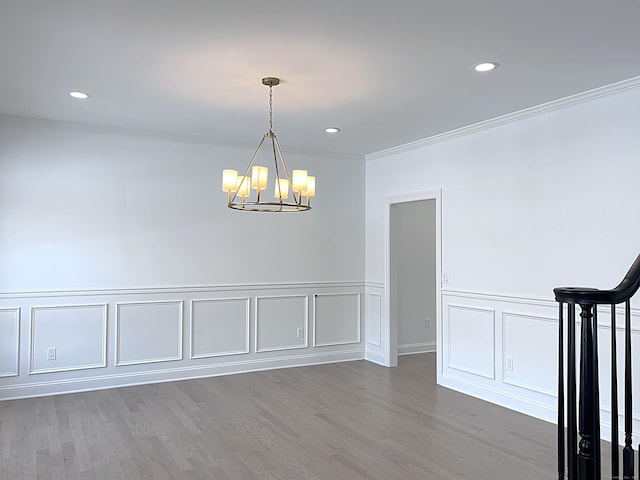 spare room with an inviting chandelier, crown molding, and hardwood / wood-style floors