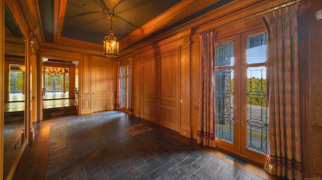 interior space featuring a raised ceiling, french doors, and wooden walls