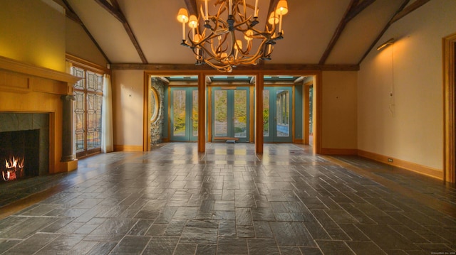 interior space featuring a fireplace, vaulted ceiling with beams, french doors, and an inviting chandelier