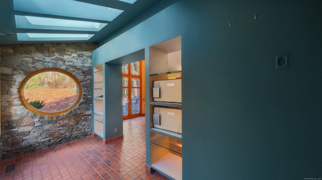 hallway with vaulted ceiling with skylight