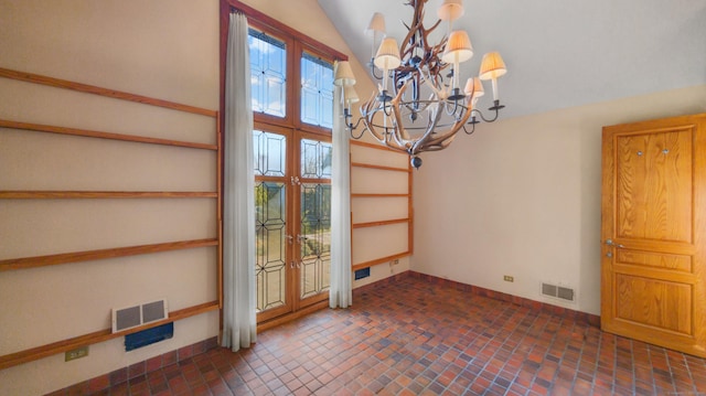 interior space with a notable chandelier, lofted ceiling, and french doors