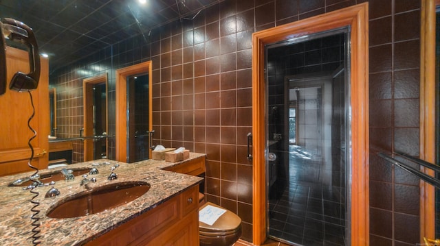 bathroom featuring toilet, vanity, and tile walls