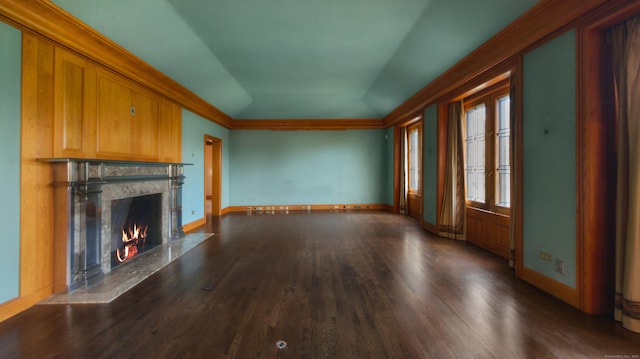 unfurnished living room with dark wood-type flooring, vaulted ceiling, a high end fireplace, and crown molding