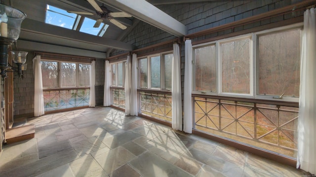 unfurnished sunroom with ceiling fan and vaulted ceiling with skylight