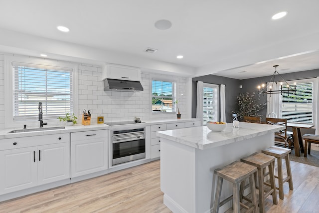 kitchen featuring sink, white cabinetry, black electric cooktop, a kitchen island, and oven