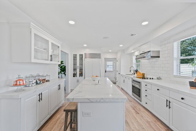 kitchen featuring a center island, sink, stainless steel oven, and white cabinets