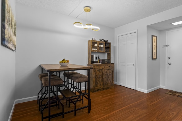 dining area with dark hardwood / wood-style flooring and a textured ceiling