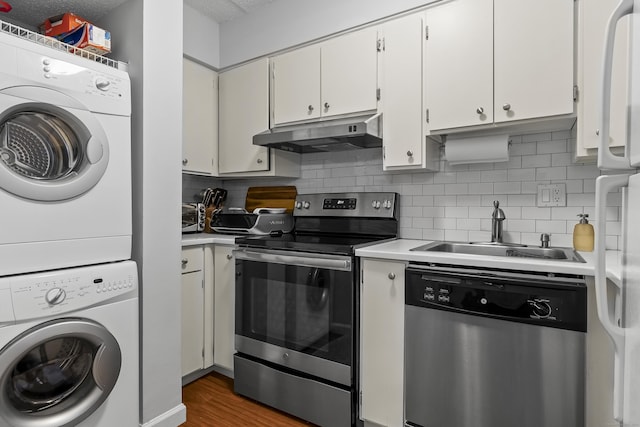 kitchen featuring appliances with stainless steel finishes, dark hardwood / wood-style flooring, sink, white cabinetry, and stacked washer / drying machine