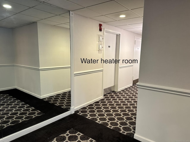 hallway featuring carpet flooring and a drop ceiling