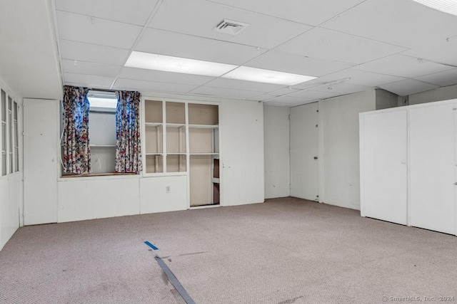 basement with a drop ceiling and light colored carpet