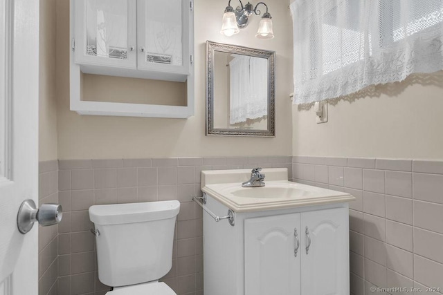 bathroom with vanity, toilet, and tile walls