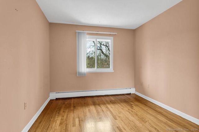 empty room featuring light hardwood / wood-style floors and a baseboard heating unit