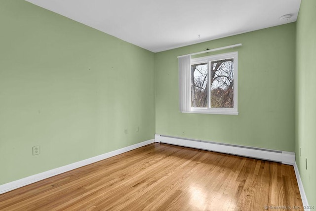 spare room featuring a baseboard radiator and light wood-type flooring