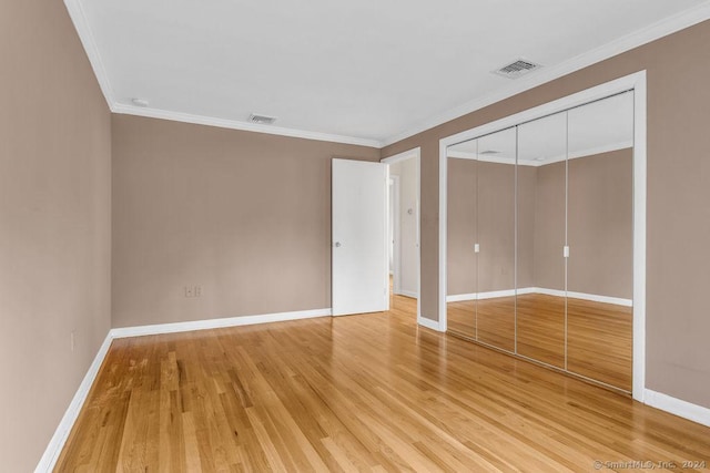 unfurnished bedroom featuring wood-type flooring, crown molding, and a closet