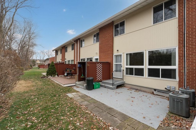 back of property with cooling unit, a deck, a yard, and a patio