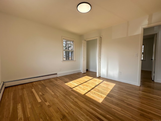 unfurnished room with hardwood / wood-style floors and a baseboard radiator