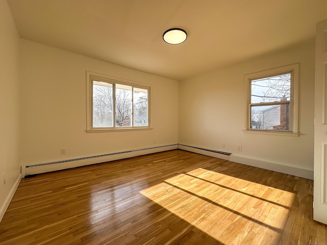 spare room with hardwood / wood-style floors and a baseboard heating unit