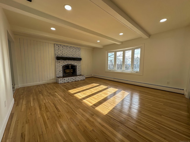 unfurnished living room with beamed ceiling, hardwood / wood-style flooring, a baseboard radiator, and a fireplace