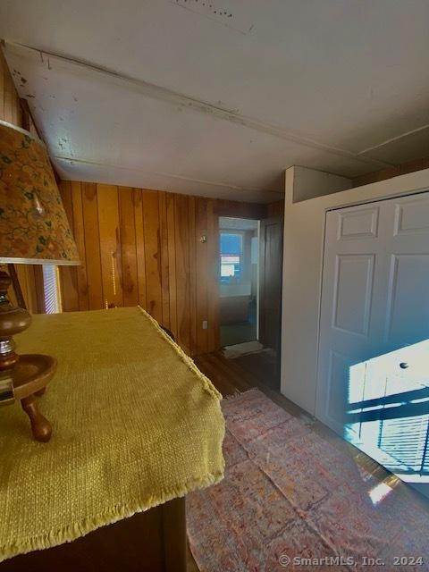 unfurnished bedroom with hardwood / wood-style flooring, wooden walls, and a closet