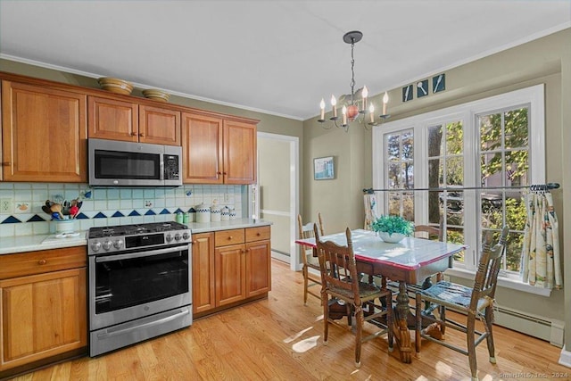 kitchen with decorative backsplash, light wood-type flooring, stainless steel appliances, crown molding, and a notable chandelier