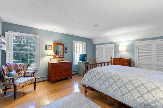 bedroom featuring baseboard heating, light hardwood / wood-style floors, and a textured ceiling