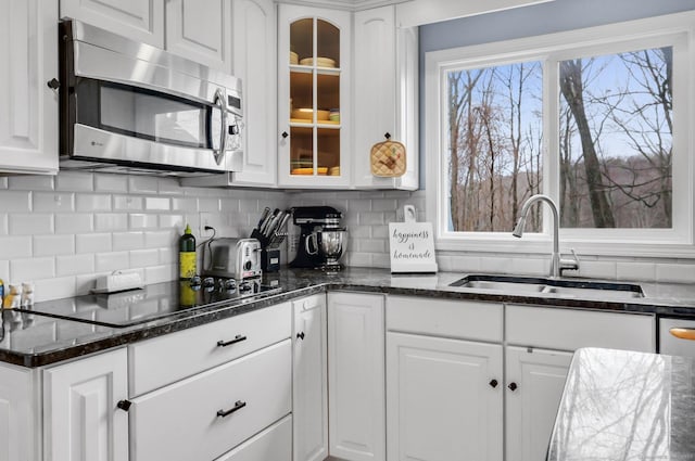 kitchen with sink, backsplash, dark stone counters, black electric cooktop, and white cabinets