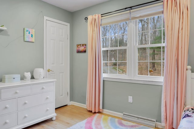 bedroom with light wood-type flooring and a baseboard radiator