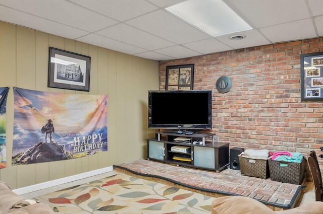 interior space featuring a paneled ceiling and brick wall